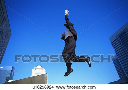 Picture - Low angle view of a person in formal attire jumping in air. Fotosearch
