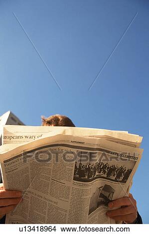 Low angle view of a person reading newspaper View Large Photo Image Picture - Low angle view of a person reading newspaper. Fotosearch