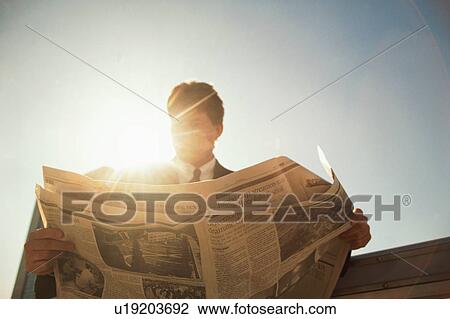 Low angle view of a person reading newspaper View Large Photo Image Stock Image - Low angle view of a person reading newspaper. Fotosearch