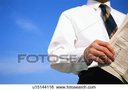 Stock Photograph - Low angle view of a person reading newspaper. Fotosearch