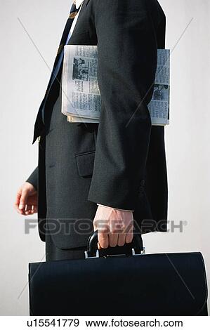 Stock Photo - Midsection of a business man holding an office bag and a newspaper. Fotosearch