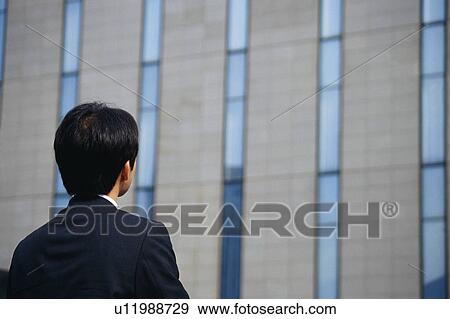 Stock Photo - Rear view of a man staring at office building. Fotosearch