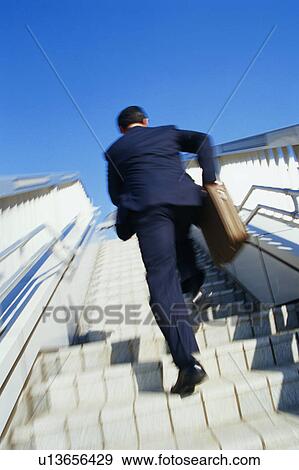 Stock Photo - Rear view of a mature man climbing stairs outside, blurred motion. Fotosearch