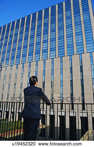 Stock Image - Rear view of a mature man staring at office building. Fotosearch