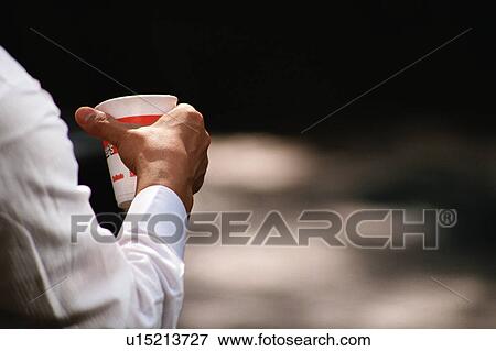 Rear view of a person holding a disposable cup View Large Photo Image Stock Photo - Rear view of a person holding a disposable cup. Fotosearch