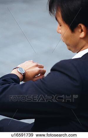 Stock Photo - Side view of a man looking at his wrist watch. Fotosearch