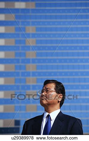 Stock Photo - Side view of a mature man in suit with commercial buildings at the back.. Fotosearch