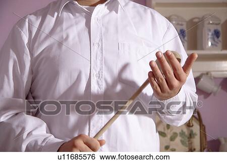 Stock Photograph - Man holding wooden spoon in a threatening gesture, close up. Fotosearch