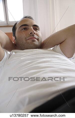 Young man lying in bed, relaxing View Large Photo Image Stock Photo - Young man lying in bed, relaxing. Fotosearch