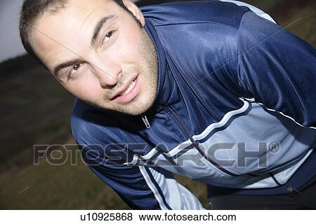 Stock Photo - Young man stretching after jogging on a rainy day. Fotosearch