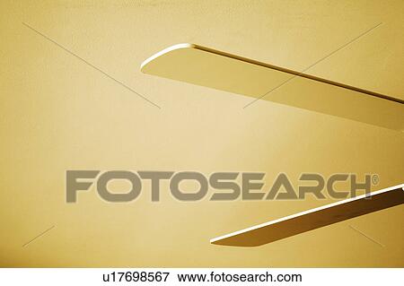Stock Photo - Blades of white ceiling fan against yellow ceiling. Fotosearch