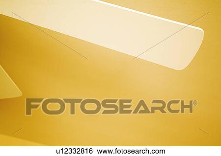 Stock Photograph - Blades of White Ceiling Fan against Yellow Ceiling. Fotosearch