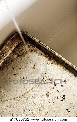 Stock Image - Running water on a dirty cookie sheet. Fotosearch