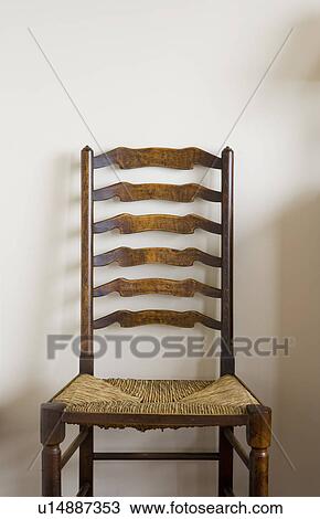 Stock Image - Detail of wood chair on white wall. Fotosearch