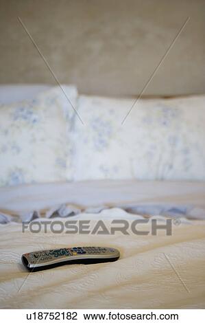 Stock Image - Television remote on bed. Fotosearch