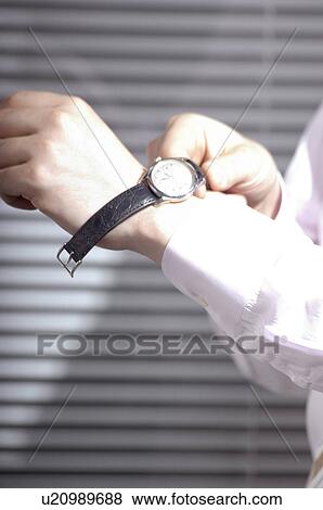 Stock Photo - Office worker putting on a watch. Fotosearch