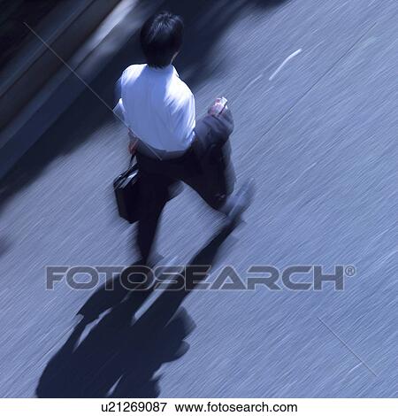 Stock Photo - A businessman walking on street, blurred motion. Fotosearch
