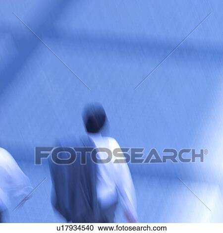 Stock Image - Businessmen walking on street, blurred motion. Fotosearch