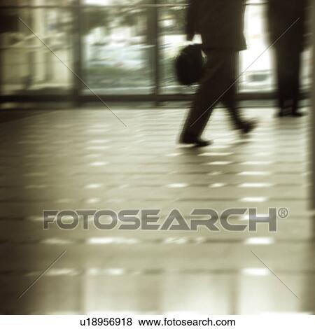 Stock Photo - Two men walking in a building, blurred motion. Fotosearch