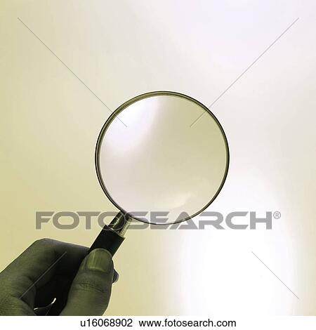 Stock Image - A man holding a magnifying glass. Fotosearch