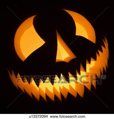 Carved Halloween pumpkin glowing in the dark. View Large Photo Image Picture - Carved Halloween pumpkin glowing in the dark.. Fotosearch
