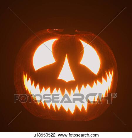 Stock Image - Carved Halloween pumpkin glowing in the dark.. Fotosearch