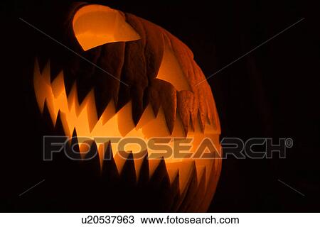 Stock Image - Carved Halloween pumpkin glowing in the dark.. Fotosearch