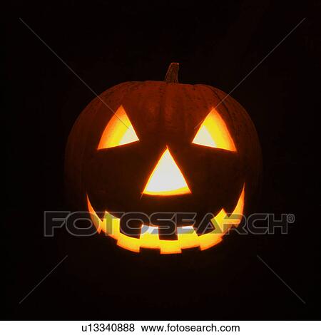 Stock Photo - Carved Halloween pumpkin glowing in the dark.. Fotosearch
