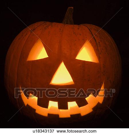 Stock Photo - Carved Halloween pumpkin glowing in the dark.. Fotosearch