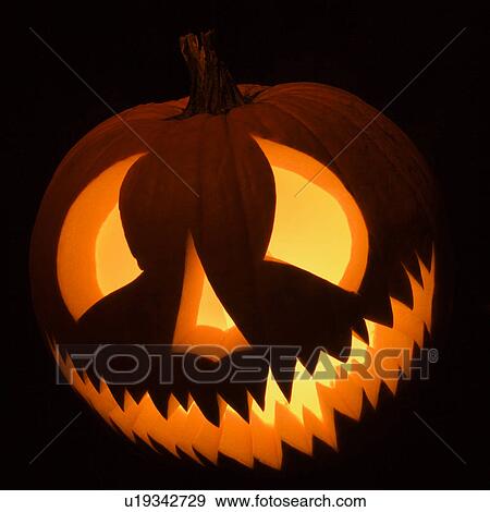 Stock Photo - Carved Halloween pumpkin glowing in the dark.. Fotosearch