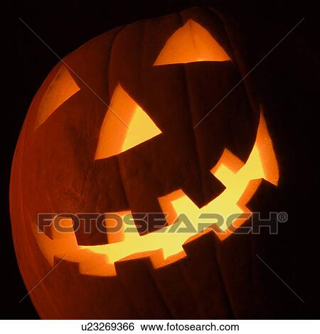 Stock Photograph - Carved Halloween pumpkin glowing in the dark.. Fotosearch