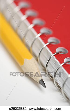 Stock Image - Close up of pencil next to spiral bound notebook. Fotosearch