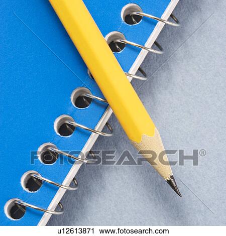 Stock Image - Sharp pencil placed on blue spiral bound notebook.. Fotosearch