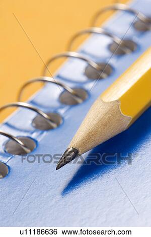 Stock Photograph - Sharp pencil placed on blue spiral bound notebook. Fotosearch