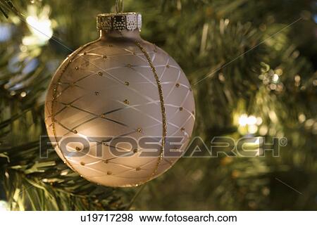 Stock Photo - Close up of gold ornament hanging in Christmas tree.. Fotosearch
