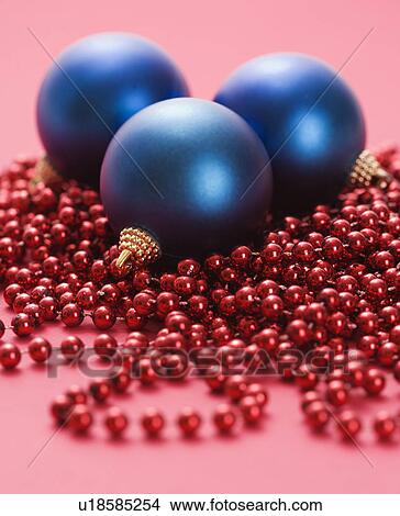Still life of large blue Christmas ornaments and strings of red beads on red background. View Large Photo Image Picture - Still life of large blue Christmas ornaments and strings of red beads on red background.. Fotosearch