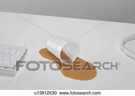 A plastic cup lies in a pool of spilt tea on a desk. View Large Photo Image Stock Image - A plastic cup lies in a pool of spilt tea on a desk.. Fotosearch