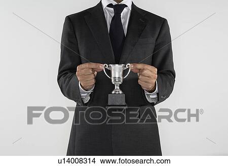 Man holding a small silver trophy. View Large Photo Image Picture - Man holding a small silver trophy.. Fotosearch
