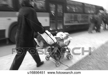 Stock Image - Rear view of woman walking with a baby in a pram on the streets of Montreal, Canada. Fotosearch