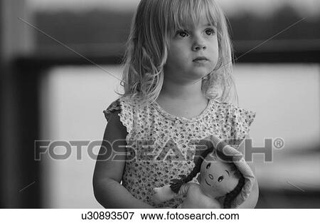 Young girl holding a doll looking up View Large Photo Image Stock Photo - Young girl holding a doll looking up. Fotosearch