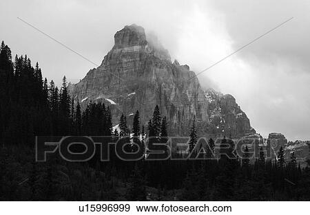 View of a mountain peak enveloped in clouds (black and white), Rocky Mountains, Canada View Large Photo Image Stock Photo - View of a mountain peak enveloped in clouds (black and white), Rocky Mountains, Canada. Fotosearch