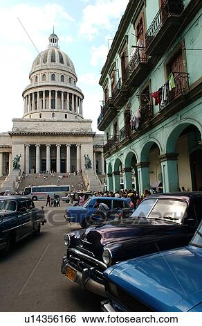 Stock Photograph - Front view of vintage cars parked outside a building. Fotosearch