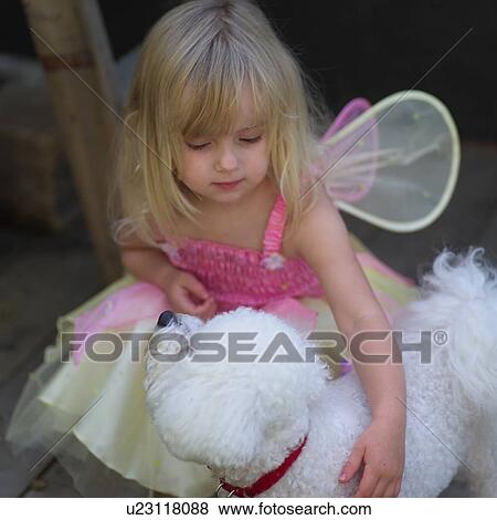 Stock Photo - Close-up of a young girl in a fairy costume holding a dog. Fotosearch