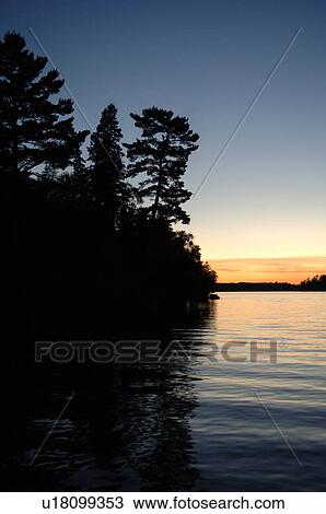 Stock Image - Silhouette of shoreline against twilight sky. Fotosearch