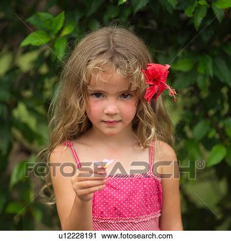Stock Image - Young girl with pink flower in her hair. Fotosearch