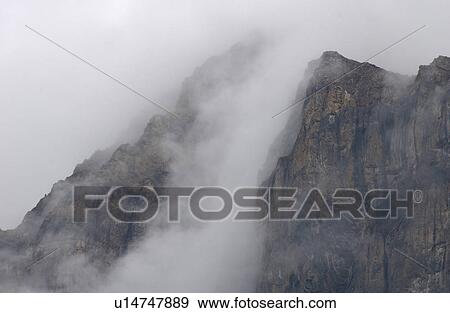 Stock Photo - Fog enveloping a mountain, Rocky Mountains, Canada. Fotosearch