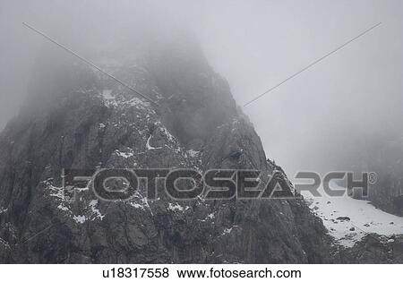 Snowy mountain range surrounded by fog in Slovenia View Large Photo Image Stock Photo - Snowy mountain range surrounded by fog in Slovenia. Fotosearch