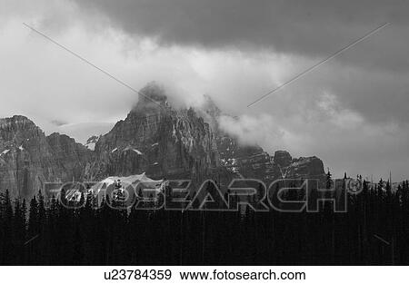Stock Photo - Panoramic view of a mountain peak enveloped in clouds, Rocky Mountains, Canada (black and white). Fotosearch