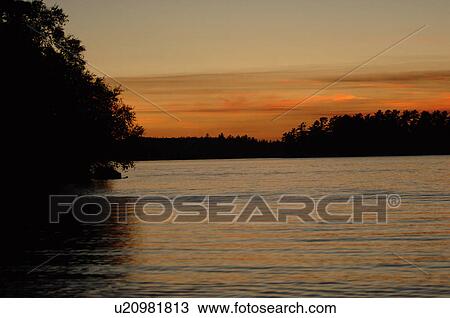 Stock Image - Silhouette of shoreline against twilight sky. Fotosearch