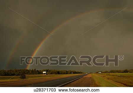 Stock Image - View of two rainbows over a highway. Fotosearch